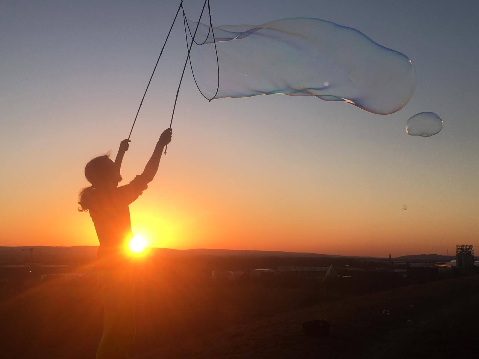 Silhouette vor dem Sonnenuntergang mit einer riesigen, in die Luft gleitenden Seifenblase