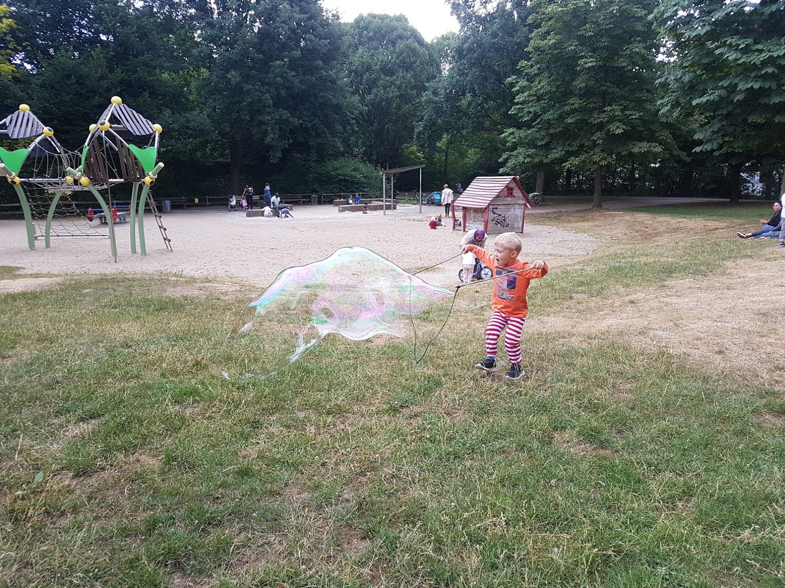 Ein kleines Kind staunt auf dem Spielplatz &uuml;ber eine gro&szlig;e Seifenblase